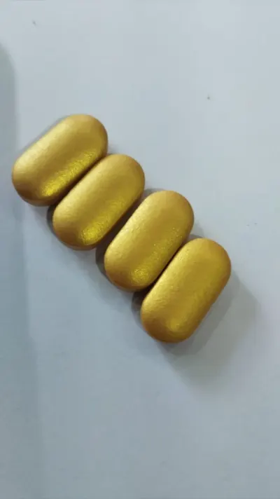 Close view of metallic gold coated caplets showing the pigment lying flat